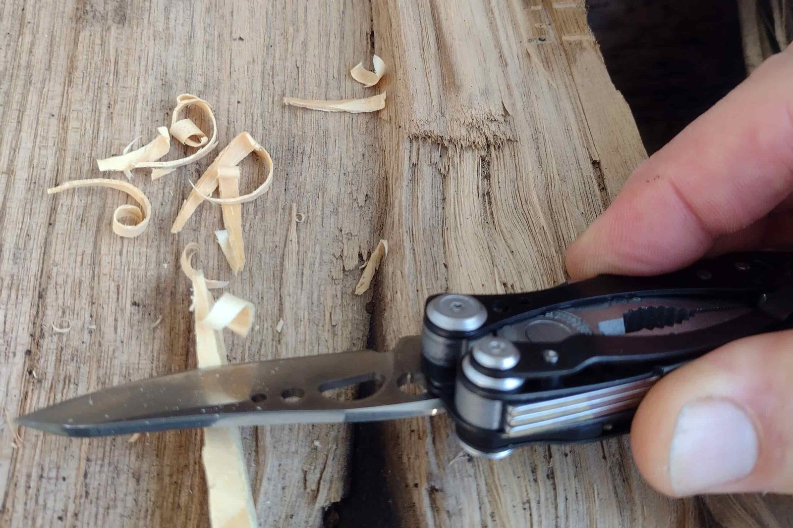 The Leatherman Skeletool CX whittling kindling shavings on top of a log.