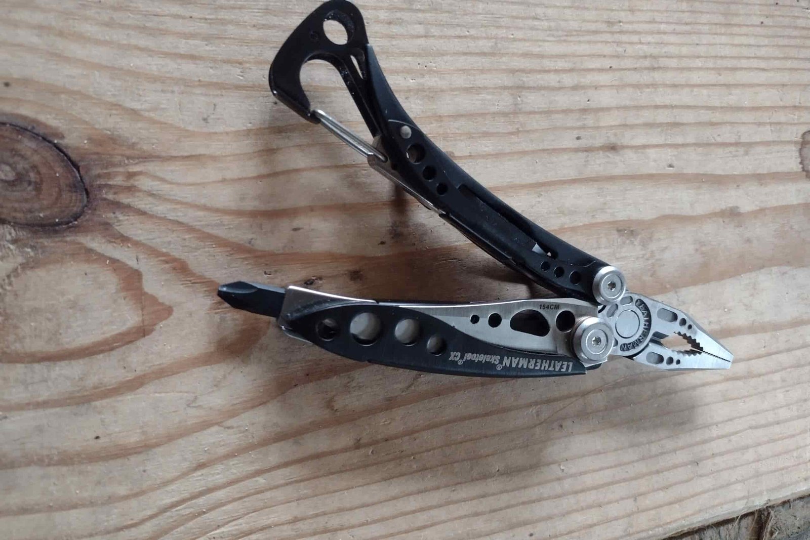 The Leatherman Skeletool CX resting on a board, with its needle nose pliers extended.
