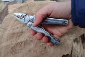 The Leatherman Surge held above a log, with its pliers extended.
