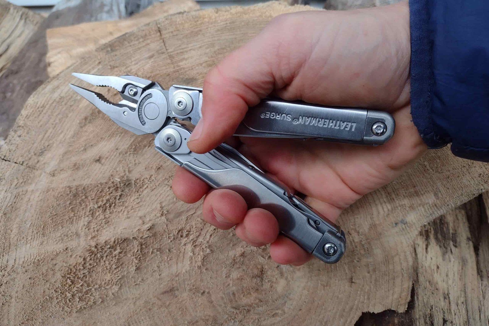 The Leatherman Surge held above a log, with its pliers extended.
