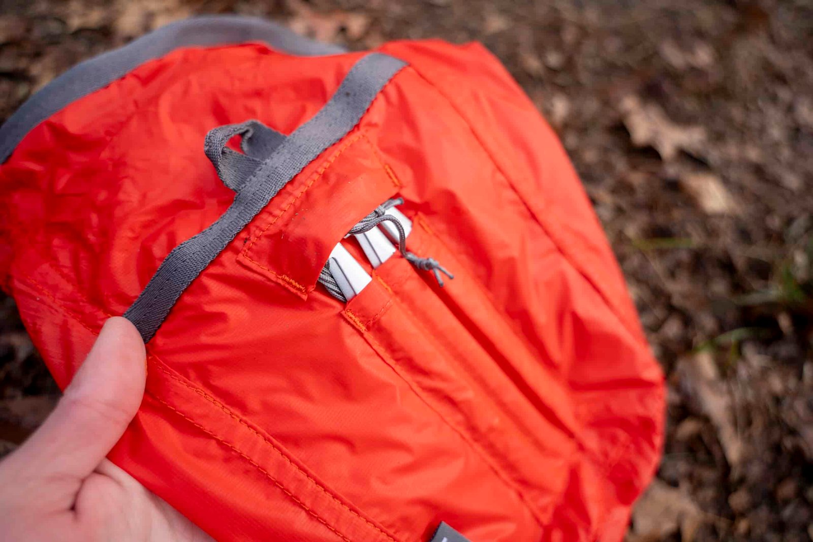 An orange bag with an exterior pocket for six tent stakes