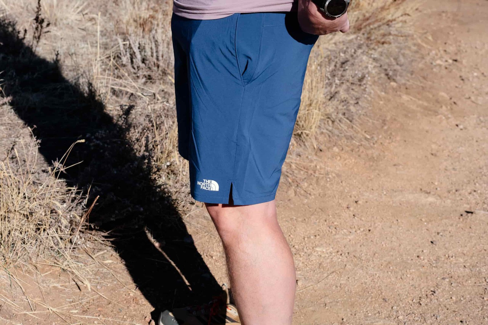 A profile of a mans legs in blue shorts.
