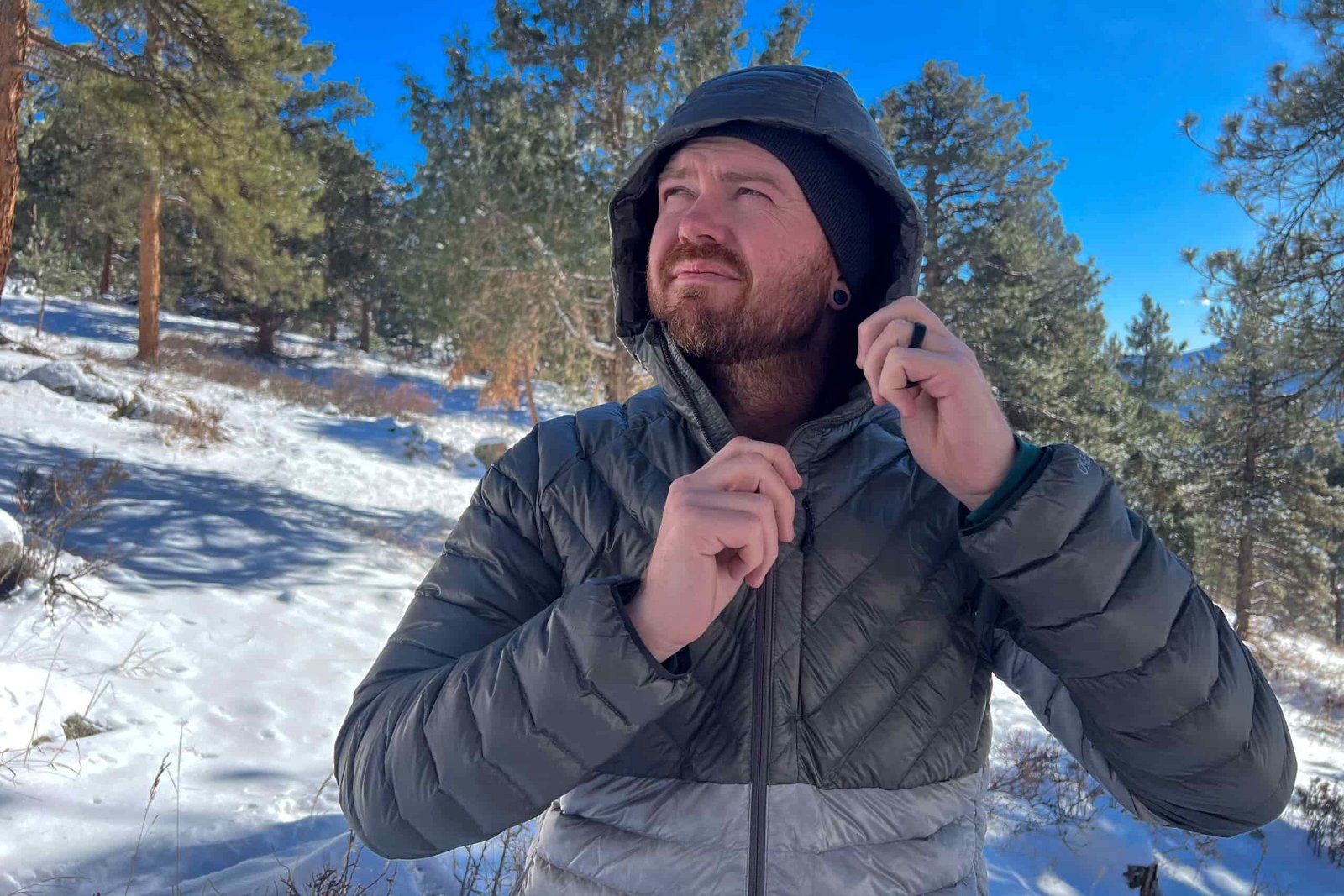 Person wearing the REI Magma 850 Down Hoody in a snowy forest, facing downward with the hood fully zipped.