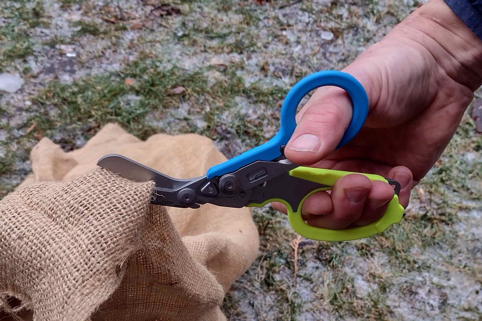 The Leatherman Raptor with blue and yellow handles cutting through burlap.