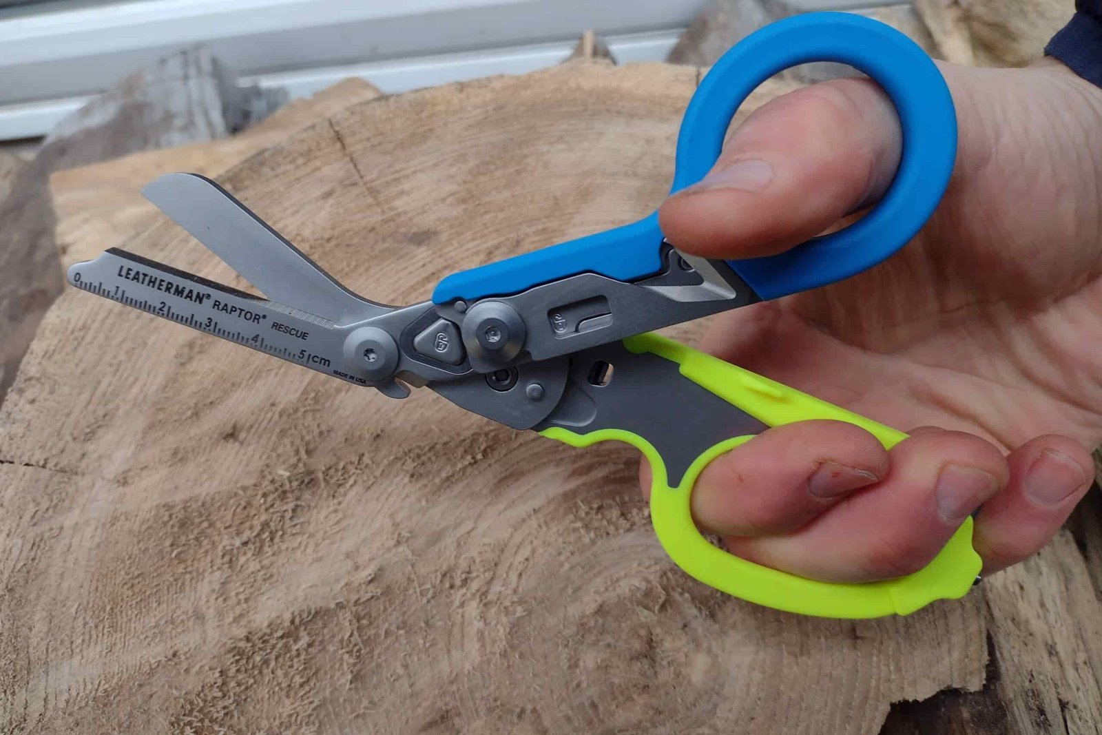 The Leatherman Raptor, held above a log.