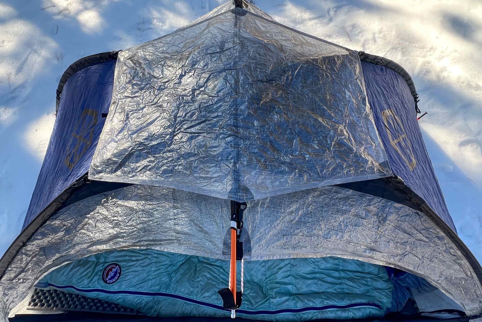 A close-up of the Samaya 2.0 tent's reflective fly, with the pole system and secure attachments visible on a snowy campsite.