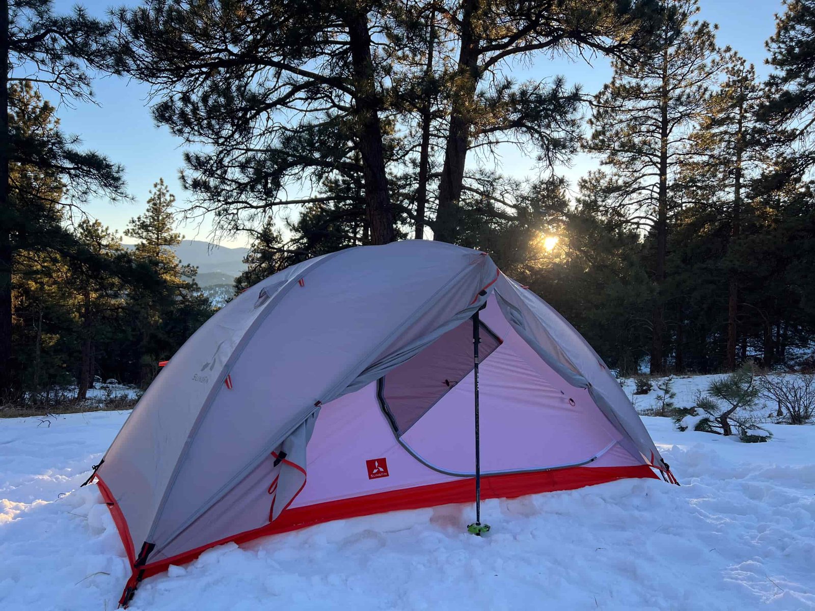 SlingFin CrossBow 2 tent with an open door revealing its interior in a snow-covered forest.