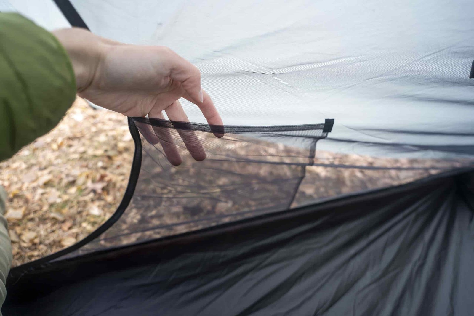 a hand holds open a pocket on the interior of a tent