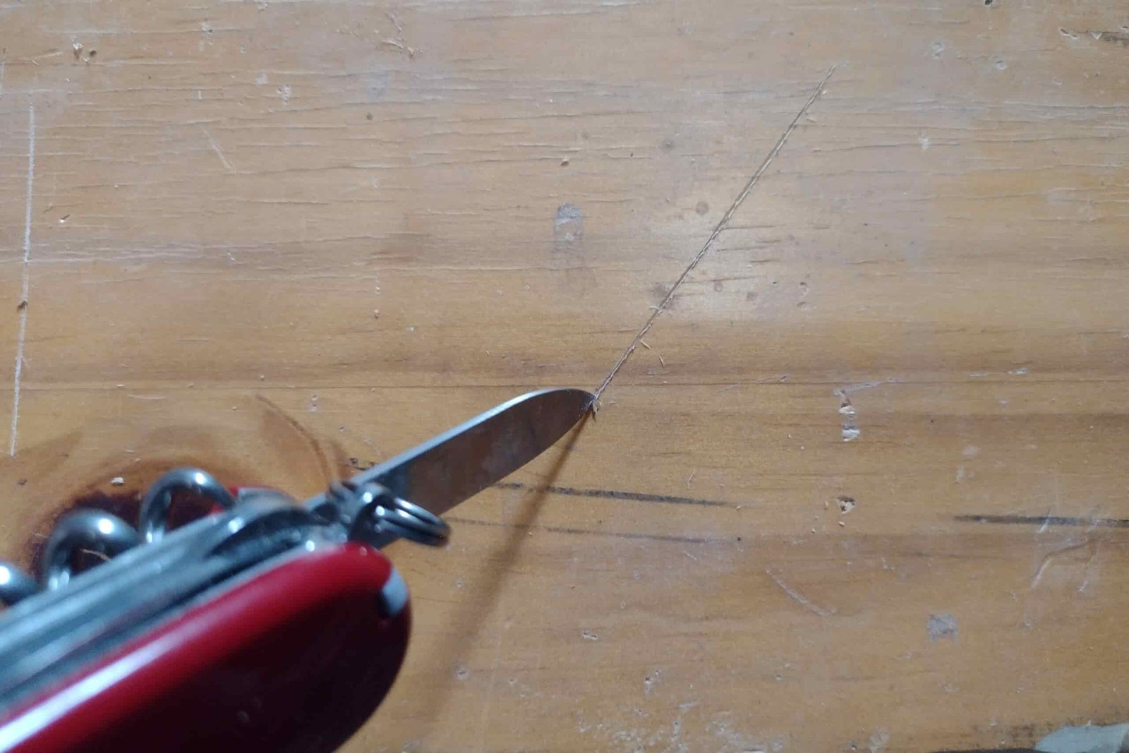 The Victorinox Huntsman cutting a line on a board with its knife blade.
