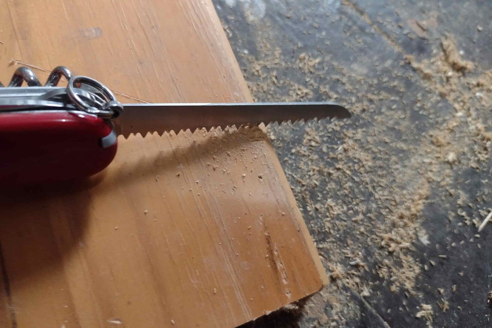 The Victorinox Huntsman with its saw cutting on a board.