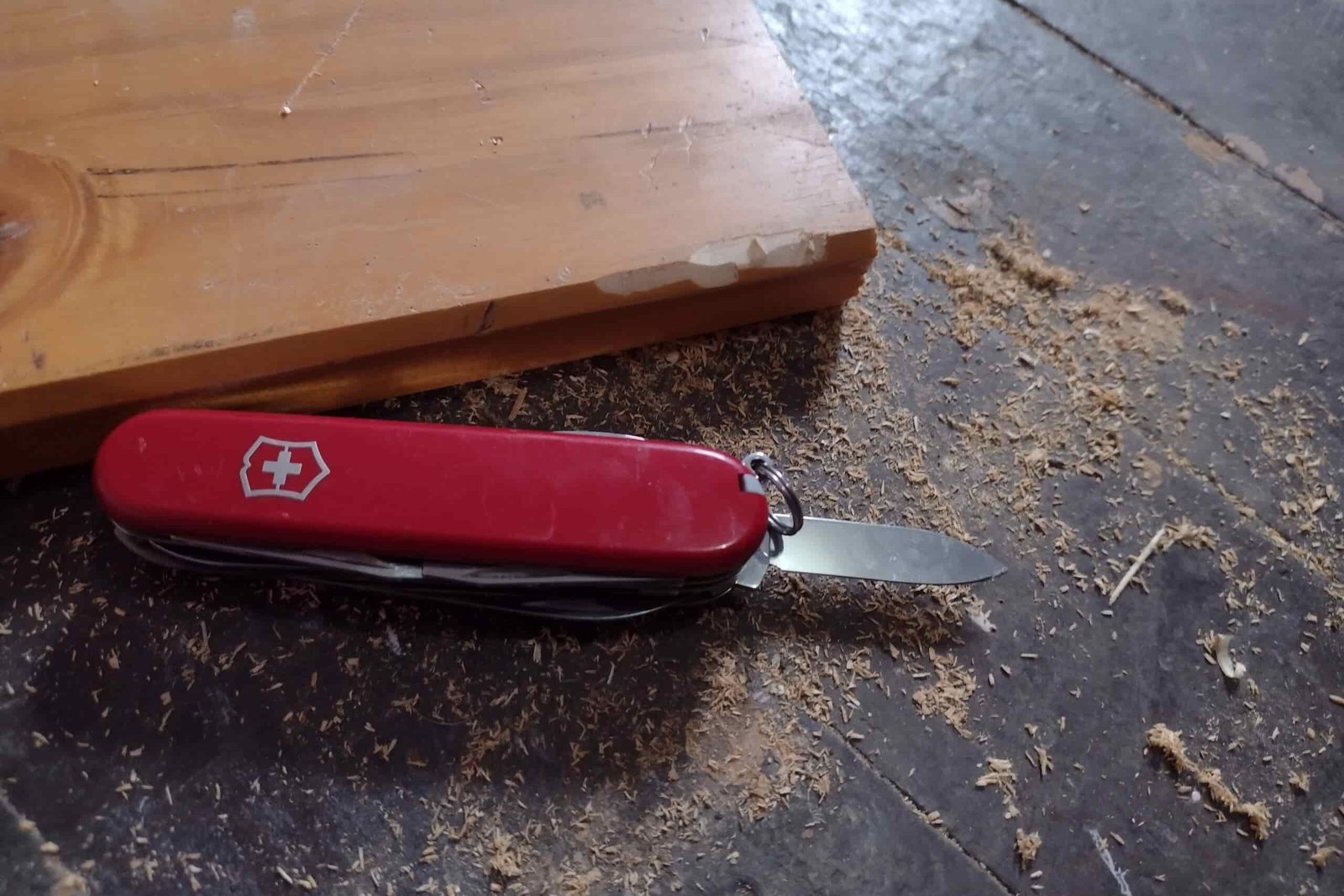 The Victorinox Huntsman with its small blade open, on a workbench next to board with sawdust around.