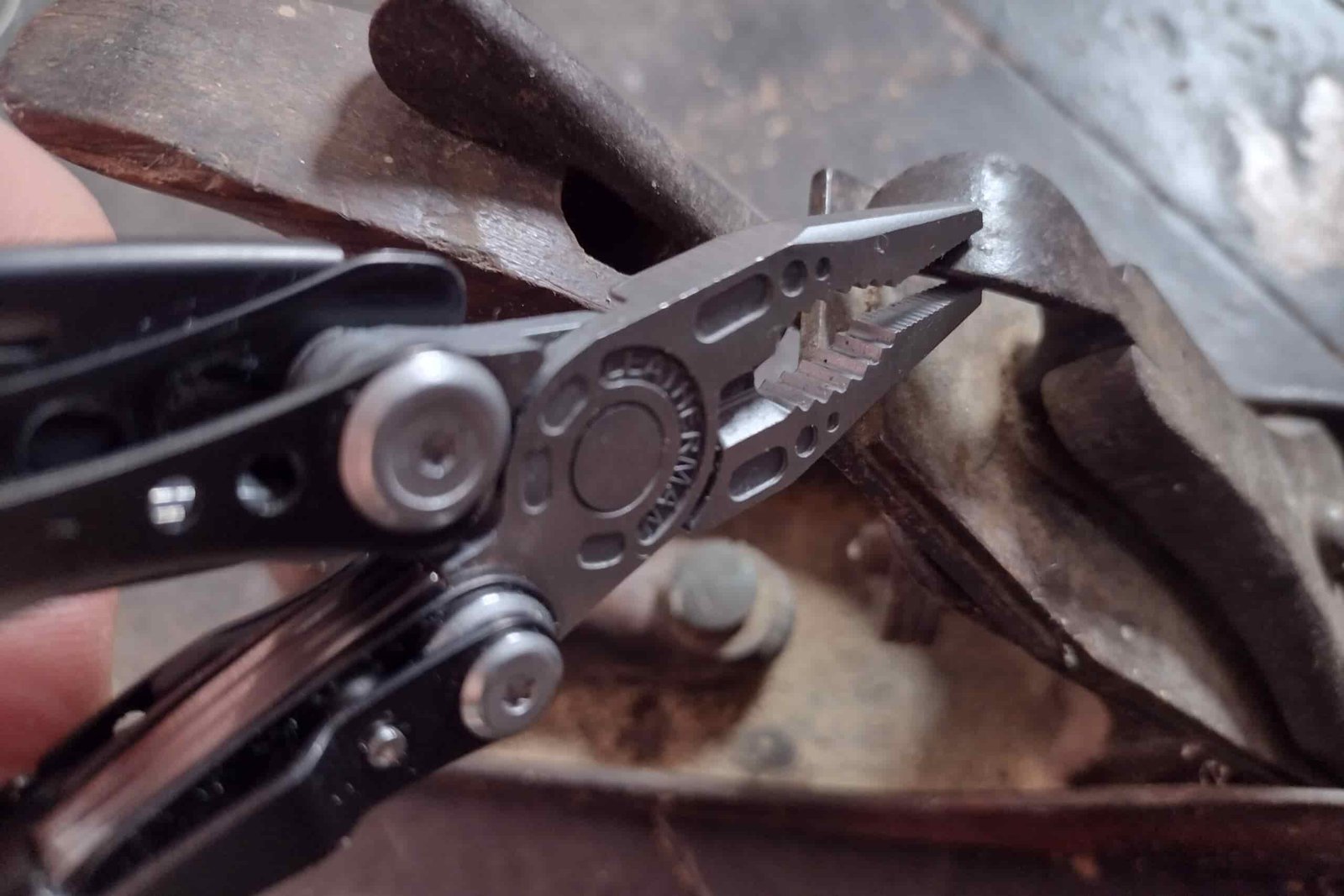 The Leatherman Skeletool gripping an old wood place with its pliers.