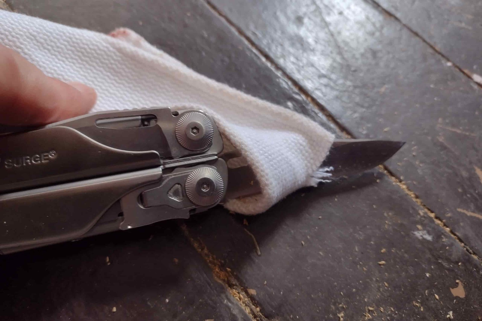 The Leatherman Surge with its blade cutting through a cloth strap.