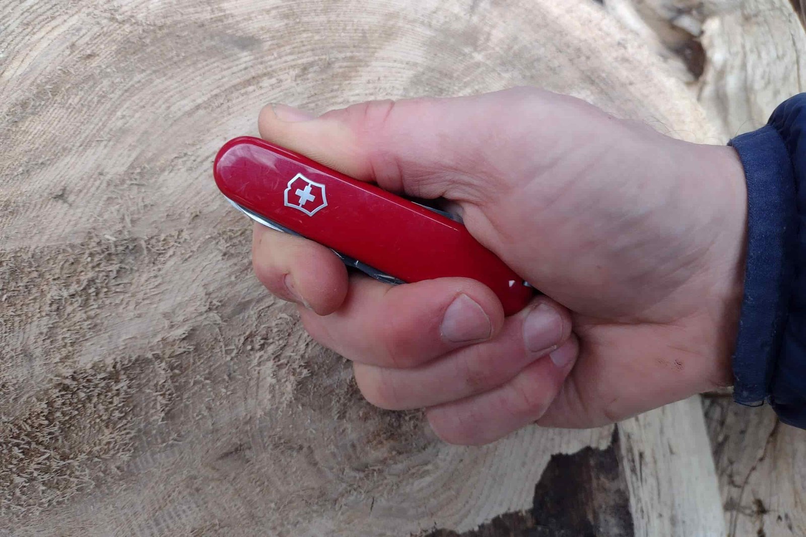 The Victorinox Rambler held in hand above a log.