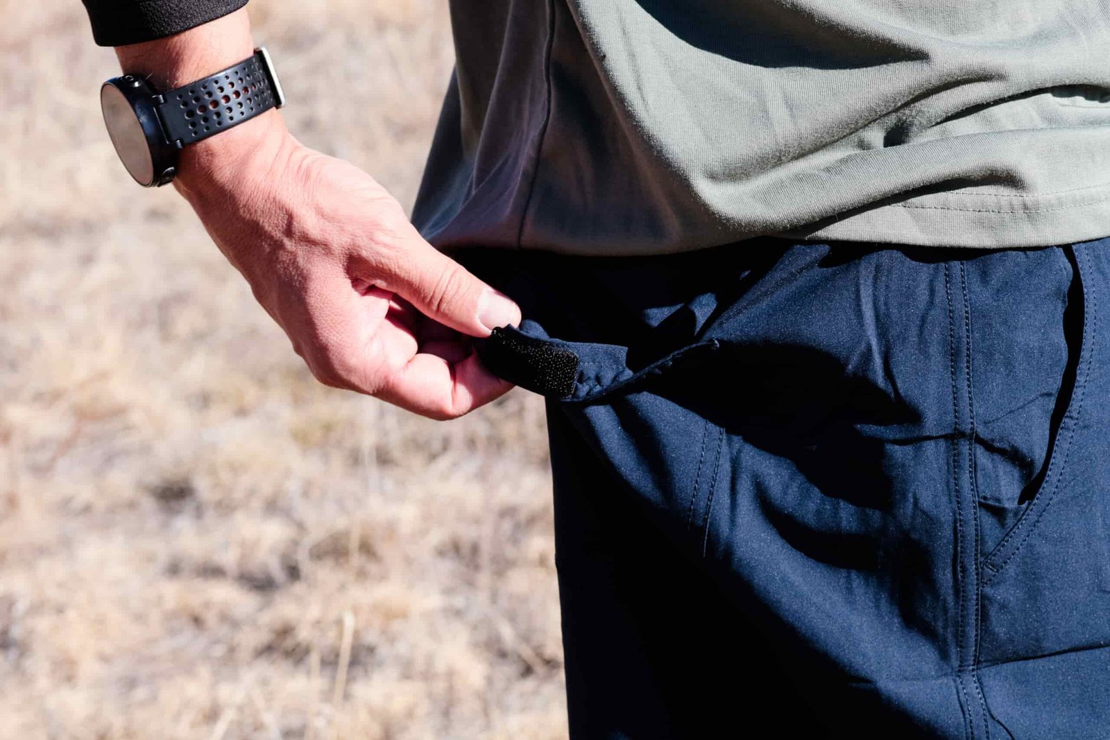 Hand opens the back pocket on shorts.