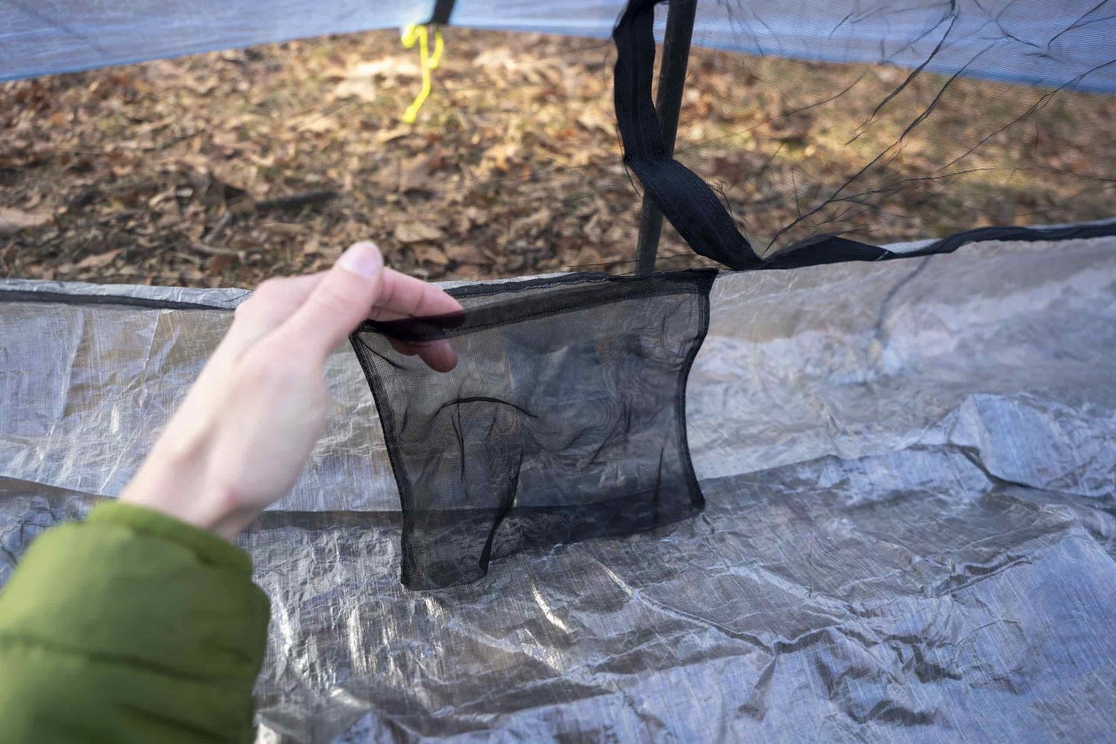 a hand holds open a mesh pocket on the interior of a tent