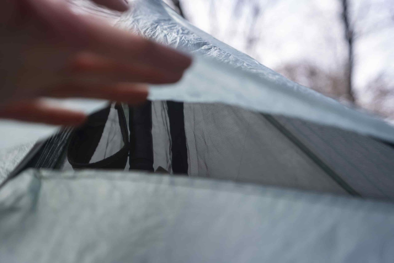a hand holds open a vent on a tent