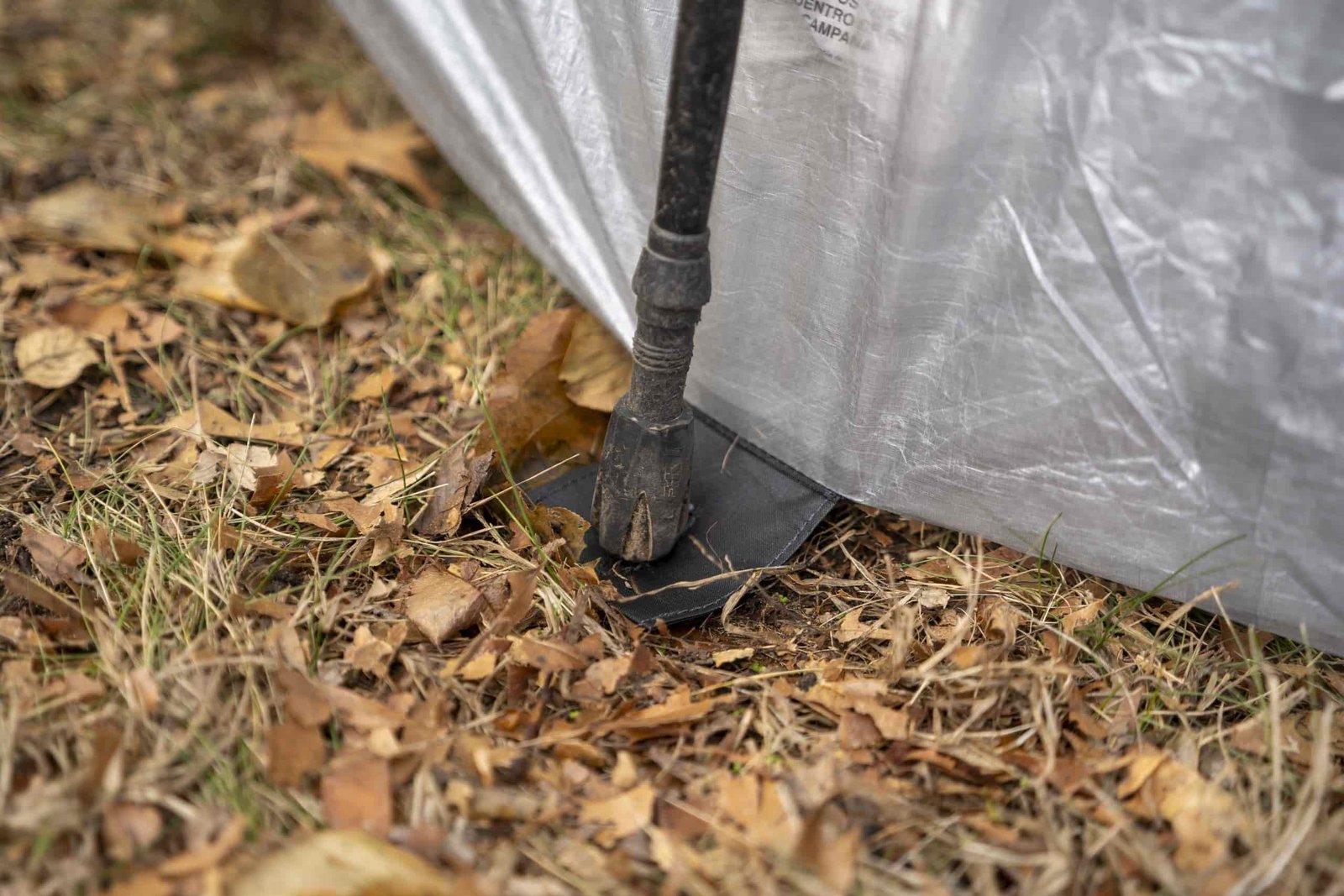 a trekking pole rests on a flap of fabric connected to a tent floor