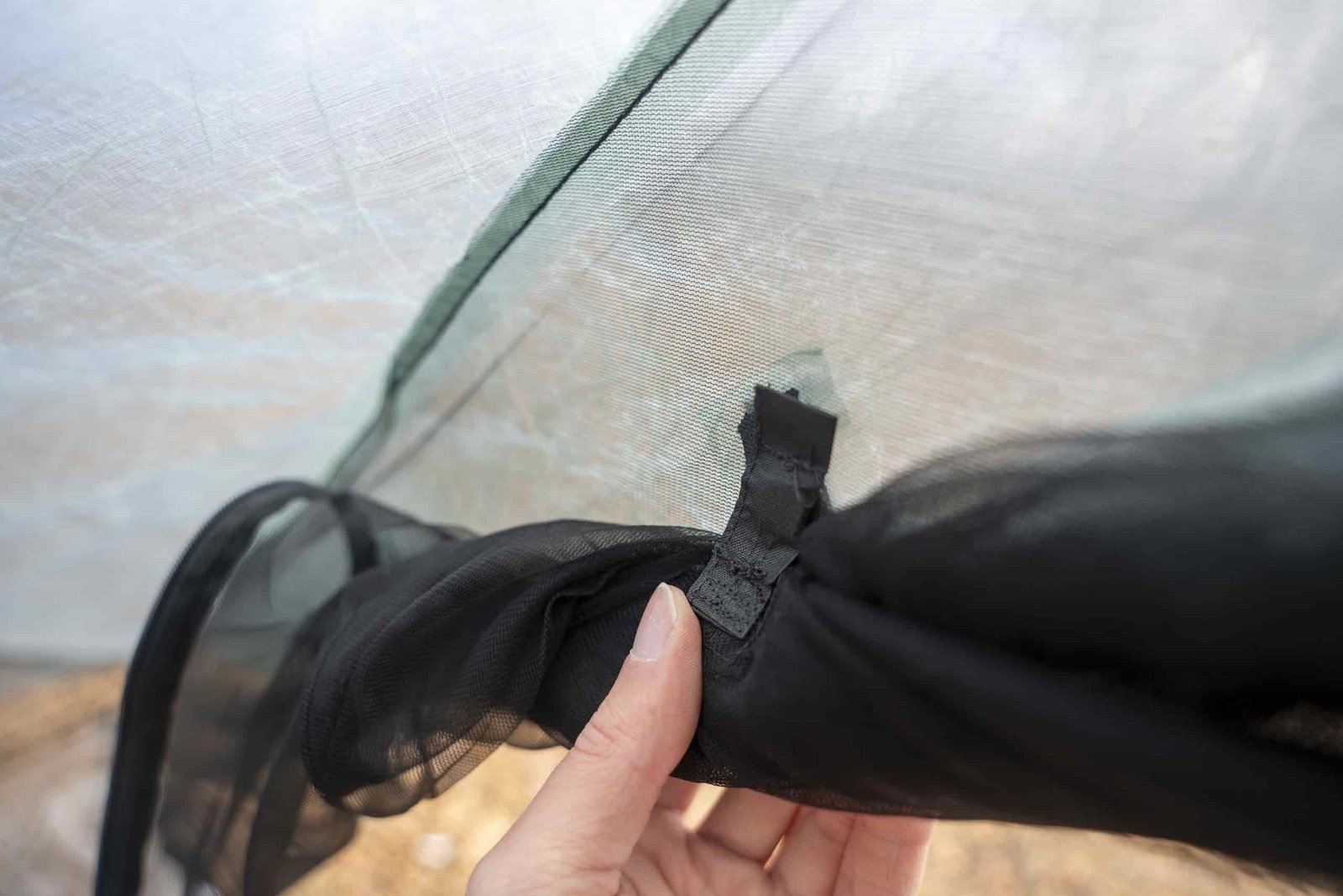 a hand holds a magnetic door closure system on a tent interior