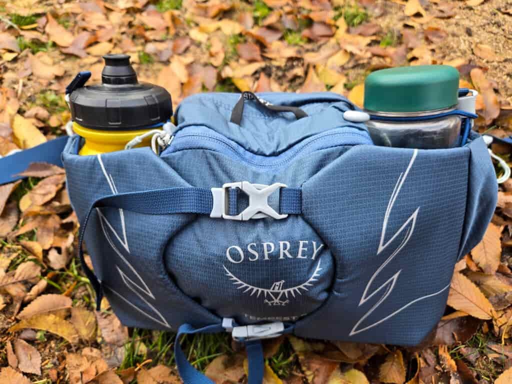 the osprey waist pack loaded with water bottles on the ground