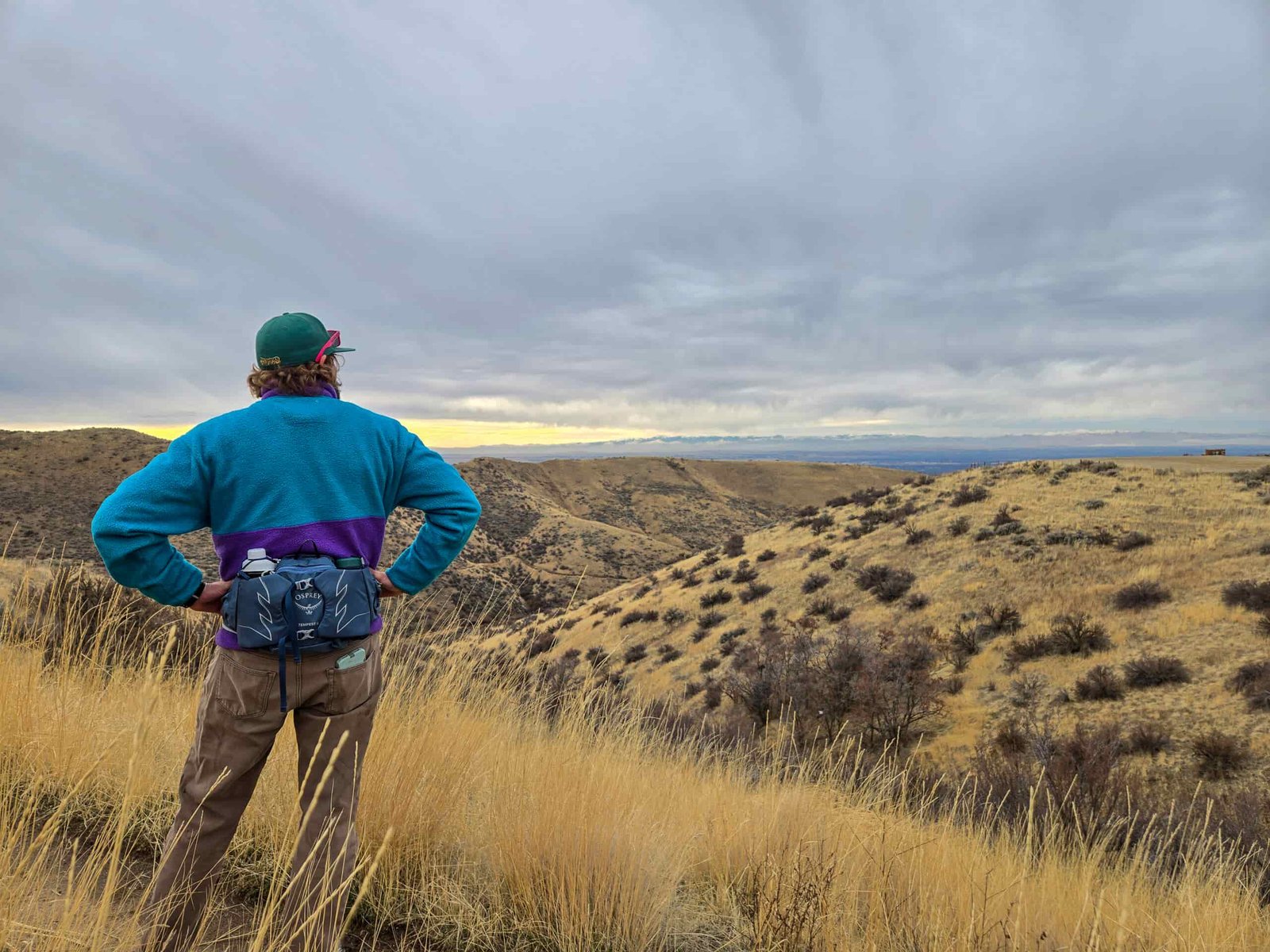 a man wearing a fanny pack by osprey looking out over a high desert prarie