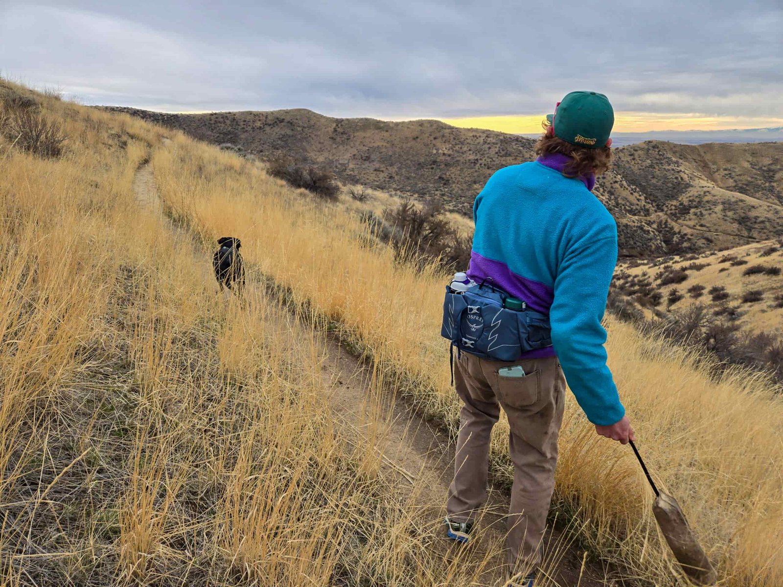 man throwing a dog toy while wearing an osprey talon waist pack