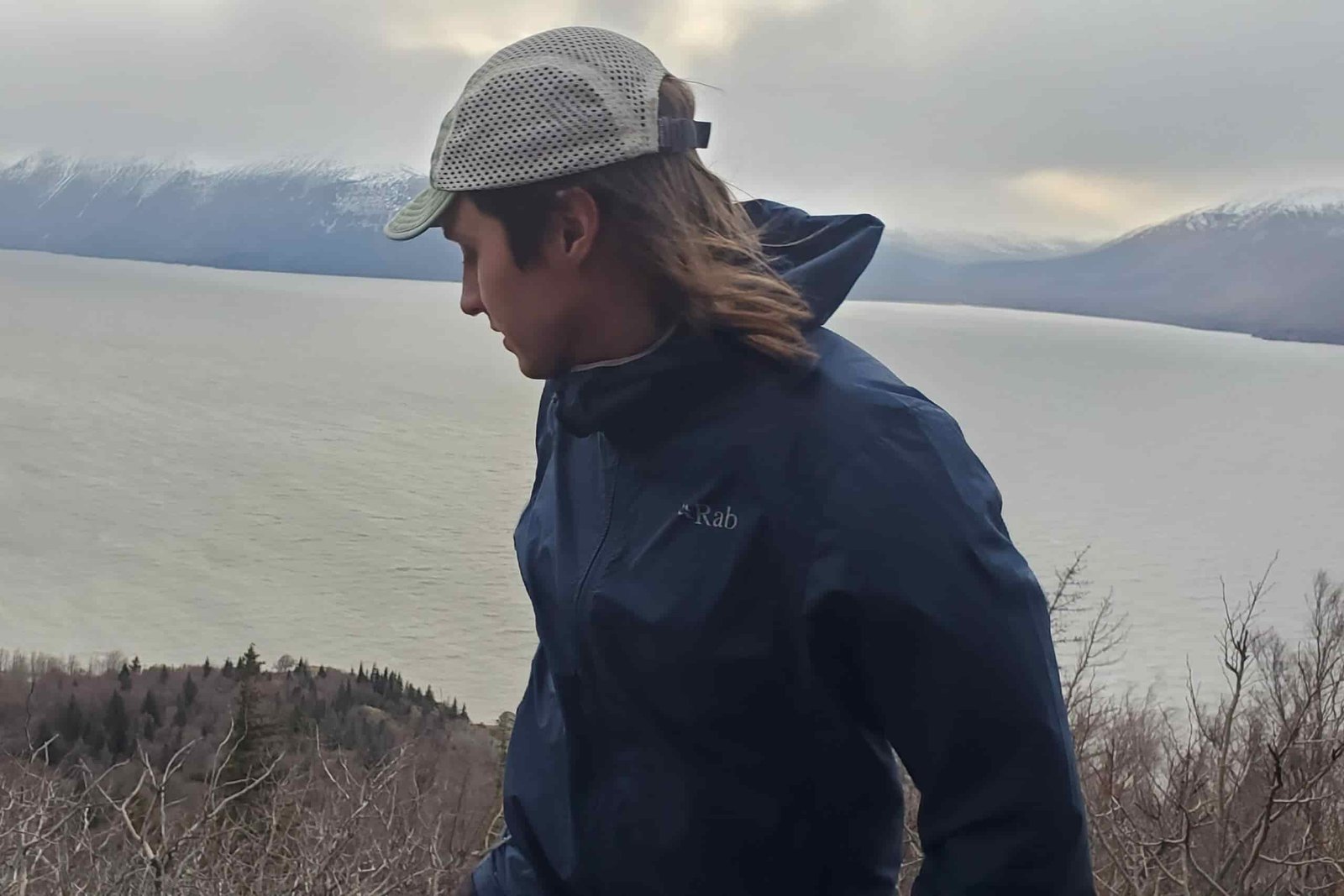 A man stands over and ocean view in strong wind.