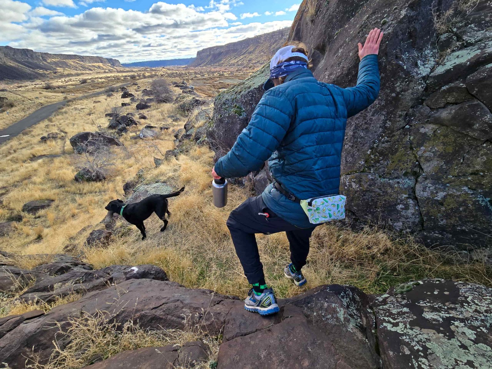 man walking down a high desert canyon trail with his dog wearing a fanny pack