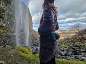 woman wearing a liteaf featherweight fanny pack while walking next to a waterfall