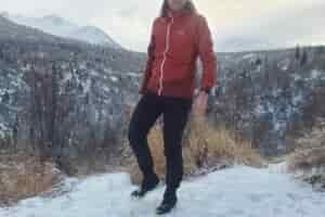 A man stands in front of a snowy canyon view.