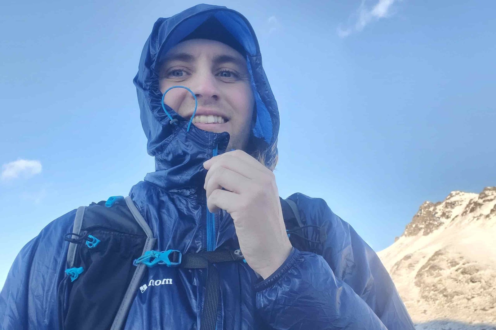 A closeup of a man wearing a hooded wind jacket.