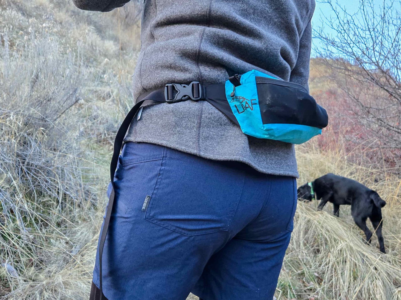a woman wearing the liteAF featherweight fanny pack on a hike with her dog