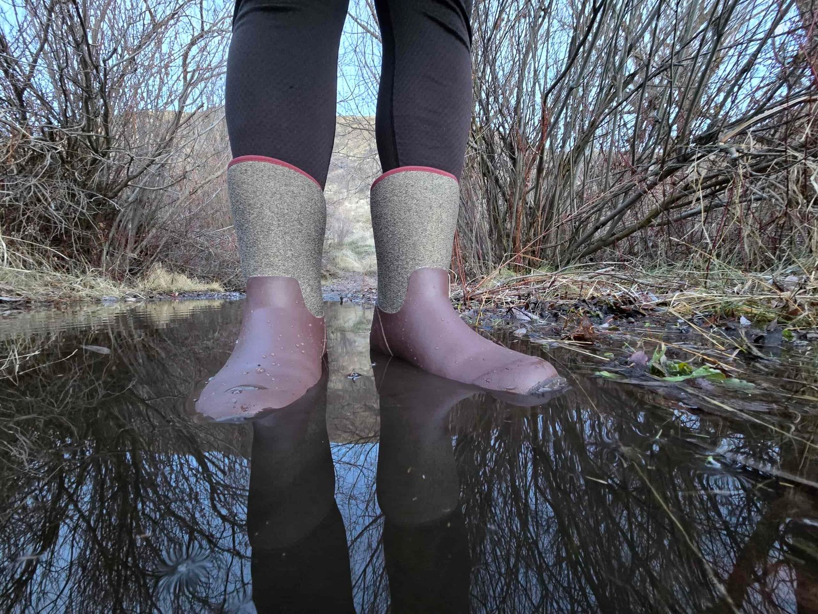 woman standing in a puddle in muck boots