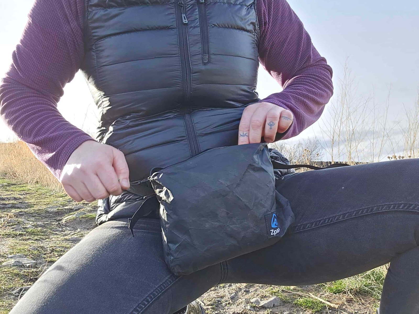 a woman croutched down upzipping her zpacks fanny pack