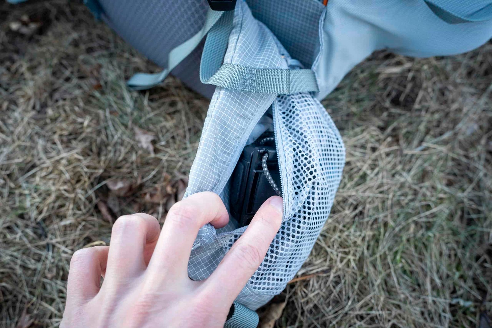 a hand holding open a backpack hipbelt pocket