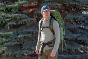 man wears a green backpack