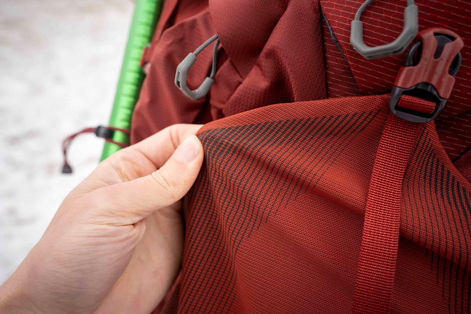 a hand holds red mesh of a backpack