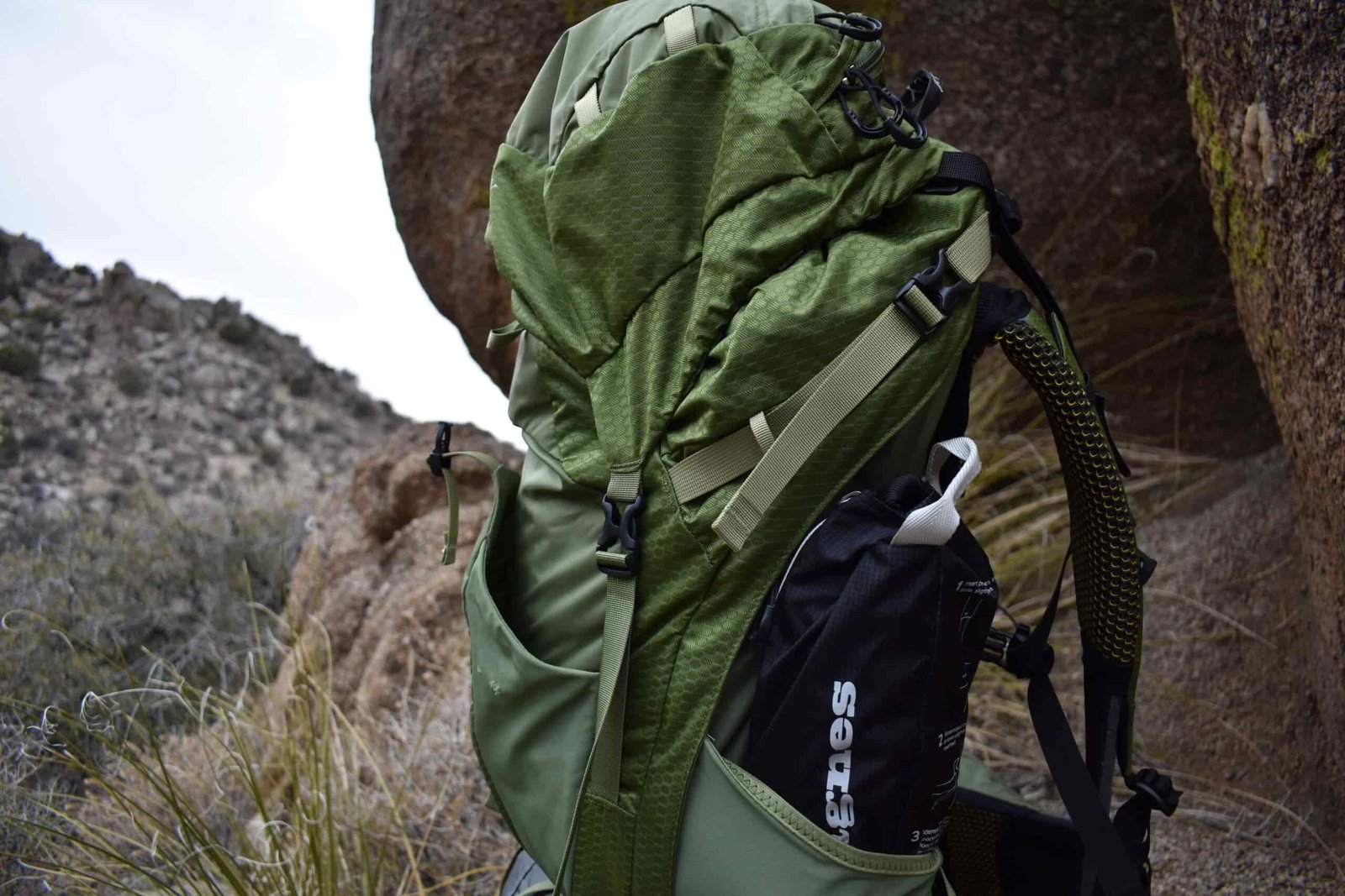 Close up of a backpack with the packed Skyline Chair stuck in its expandable side pockets.