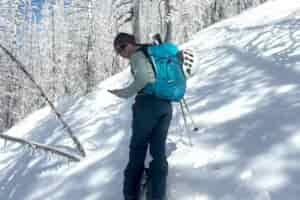 Gregory Juno 24 H2O pack used by a person on skis against a snowy hill with snowy trees on a sunny day