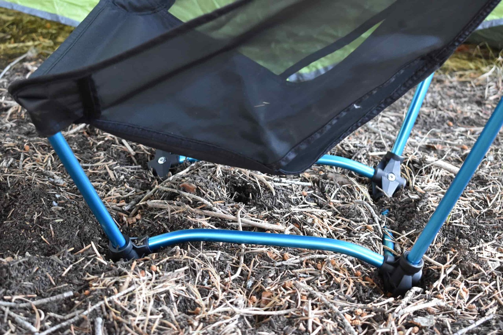 Close up of the square-shaped aluminum frame and feet of the Helinox Ground Chair setting on a soft bed of pine needles
