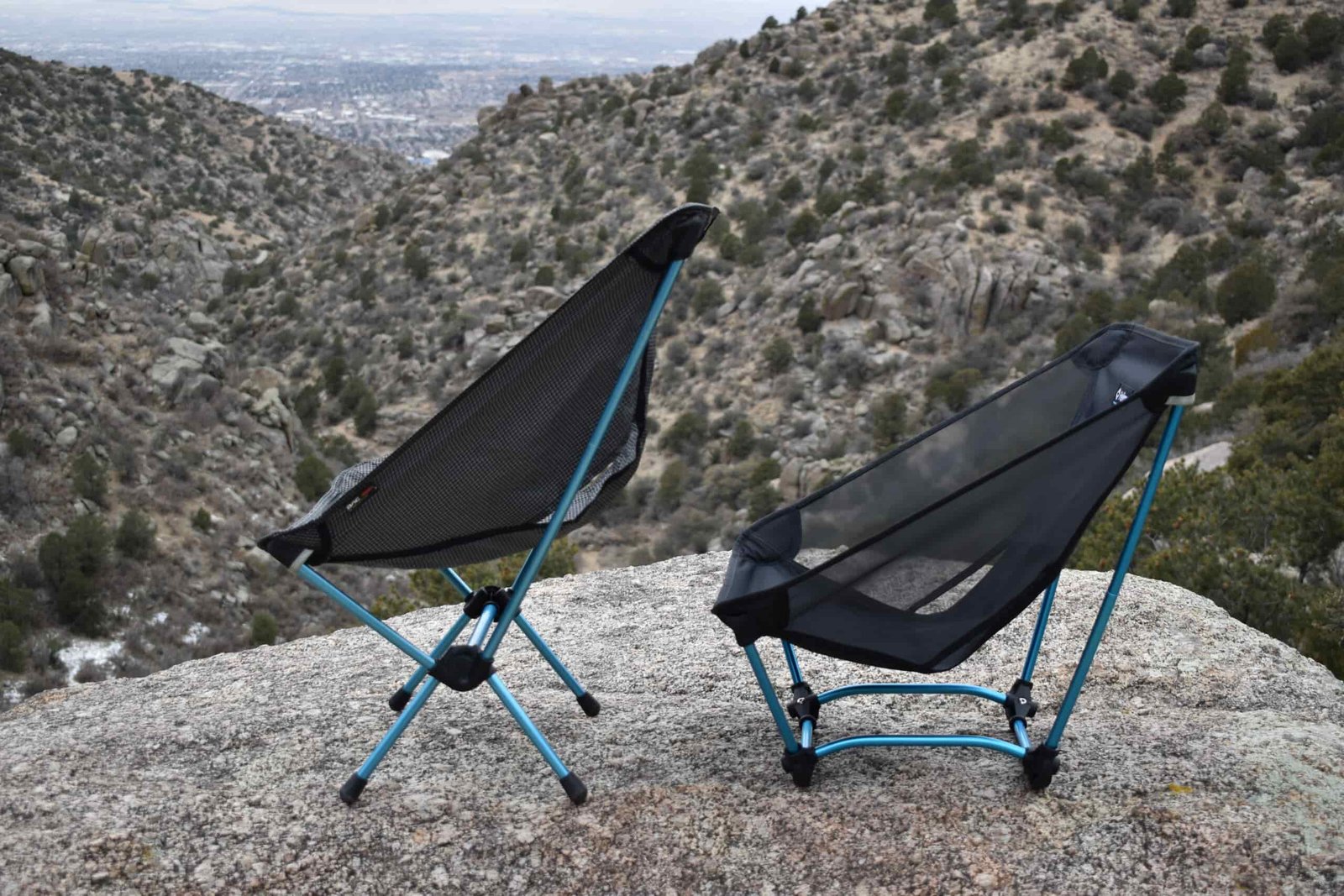 The Helinox Chair Zero and Helinox Ground chair sit side by side on a rocky outcrop to compare their seating positions