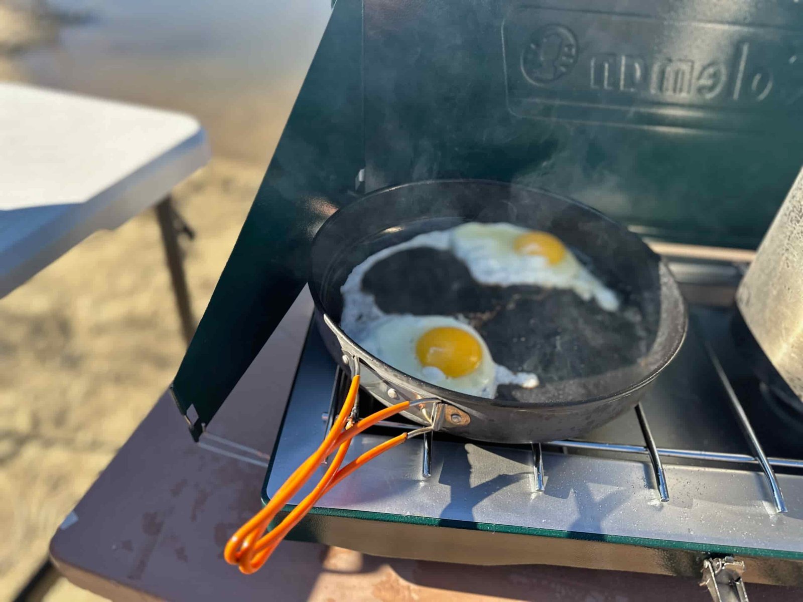 the Coleman Cascade Classic 2-Burner cooking camp meals at a beachside camp