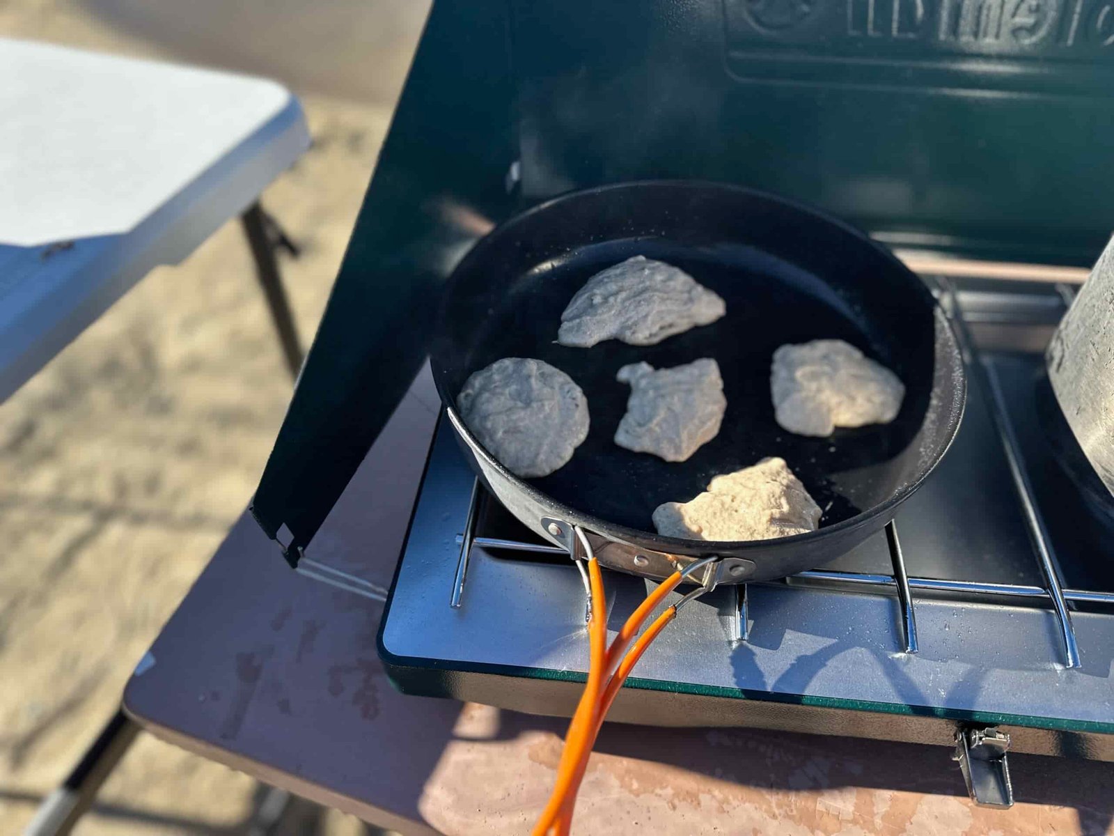 the Coleman Cascade Classic 2-Burner cooking camp meals at a beachside camp