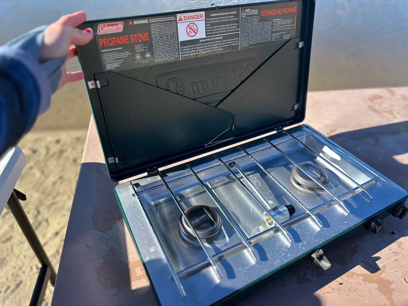 the Coleman Cascade Classic 2-Burner cooking camp meals at a beachside camp