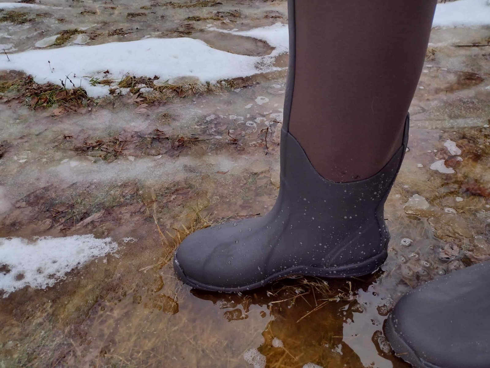 Ground level view of someone wearing the brown Original Muck Boot Wetland standing in water.