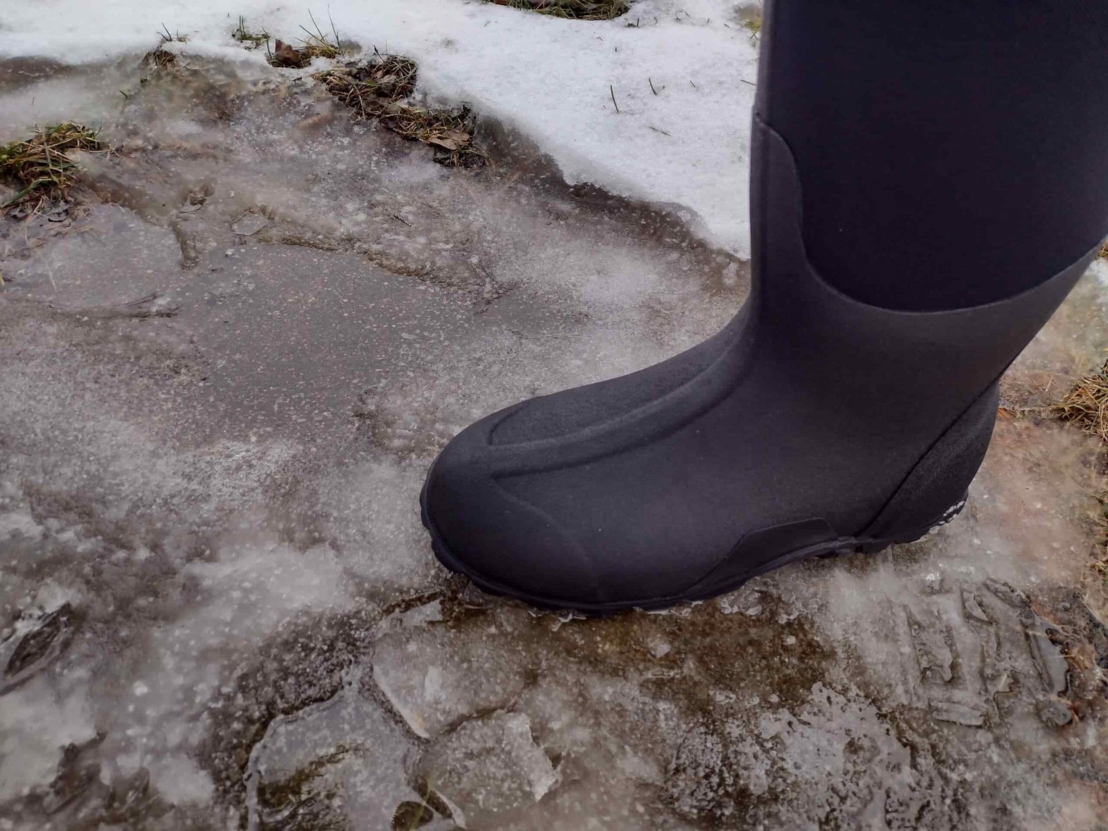 Ground level view of someone wearing the black Bogs Classic High standing on ice.
