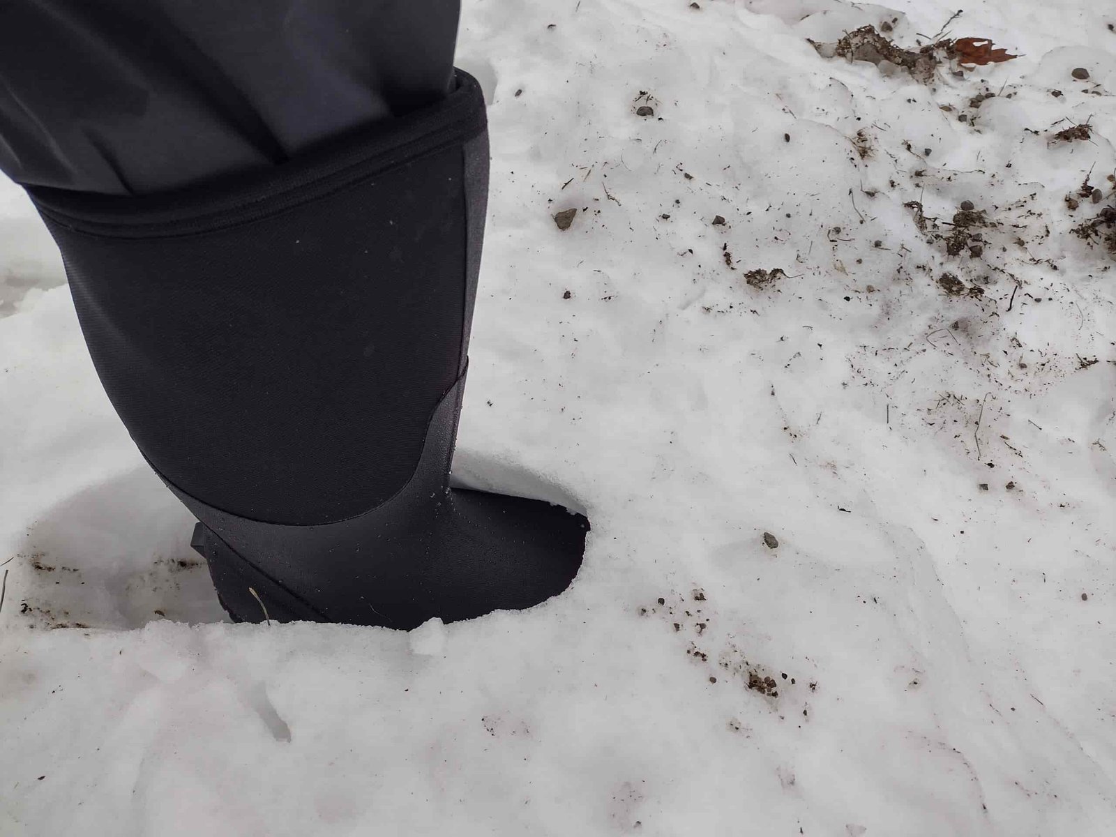 Ground level view of someone wearing the black Bogs Classic High standing in deep snow.