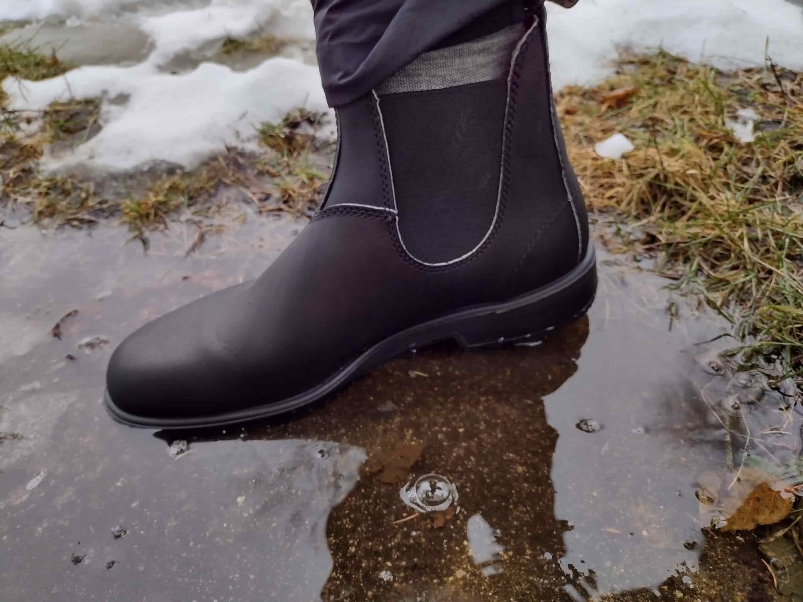 Ground level view of someone wearing the black Blundstone Original Chelsea standing in a puddle.
