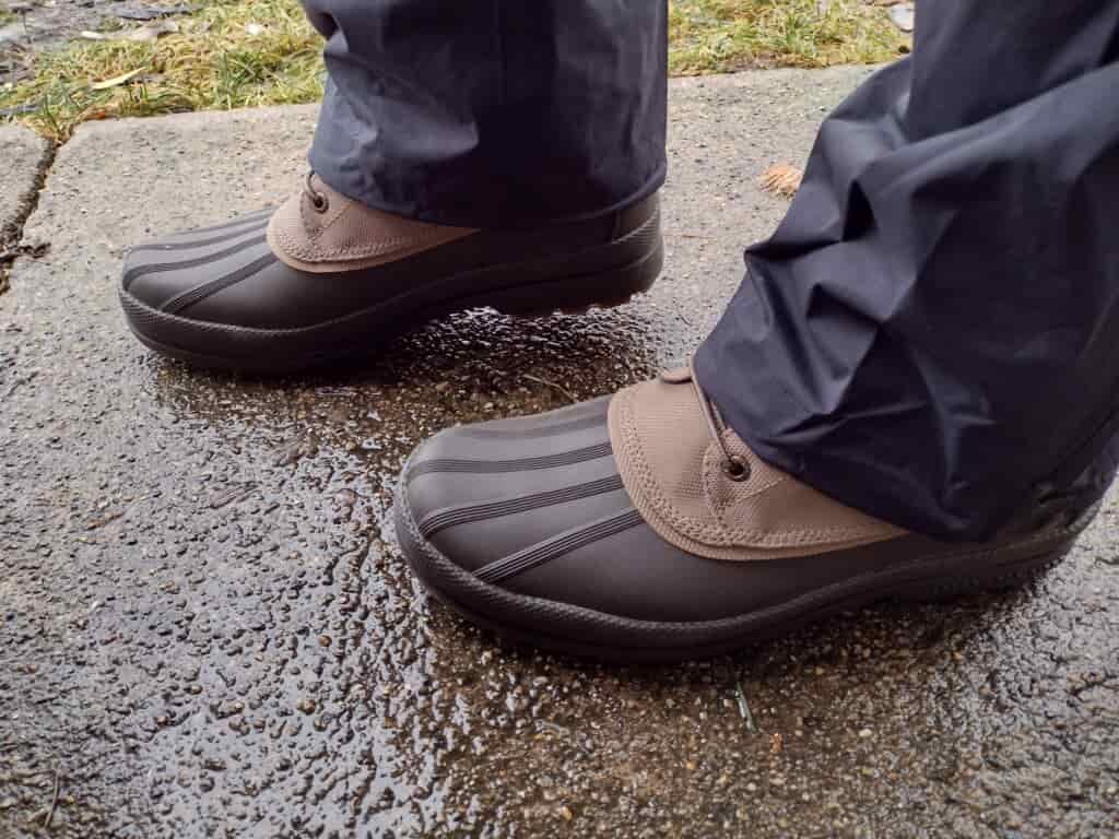 Ground level view of someone wearing the brown Sperry Cold Bay Chukka on a wet sidewalk.