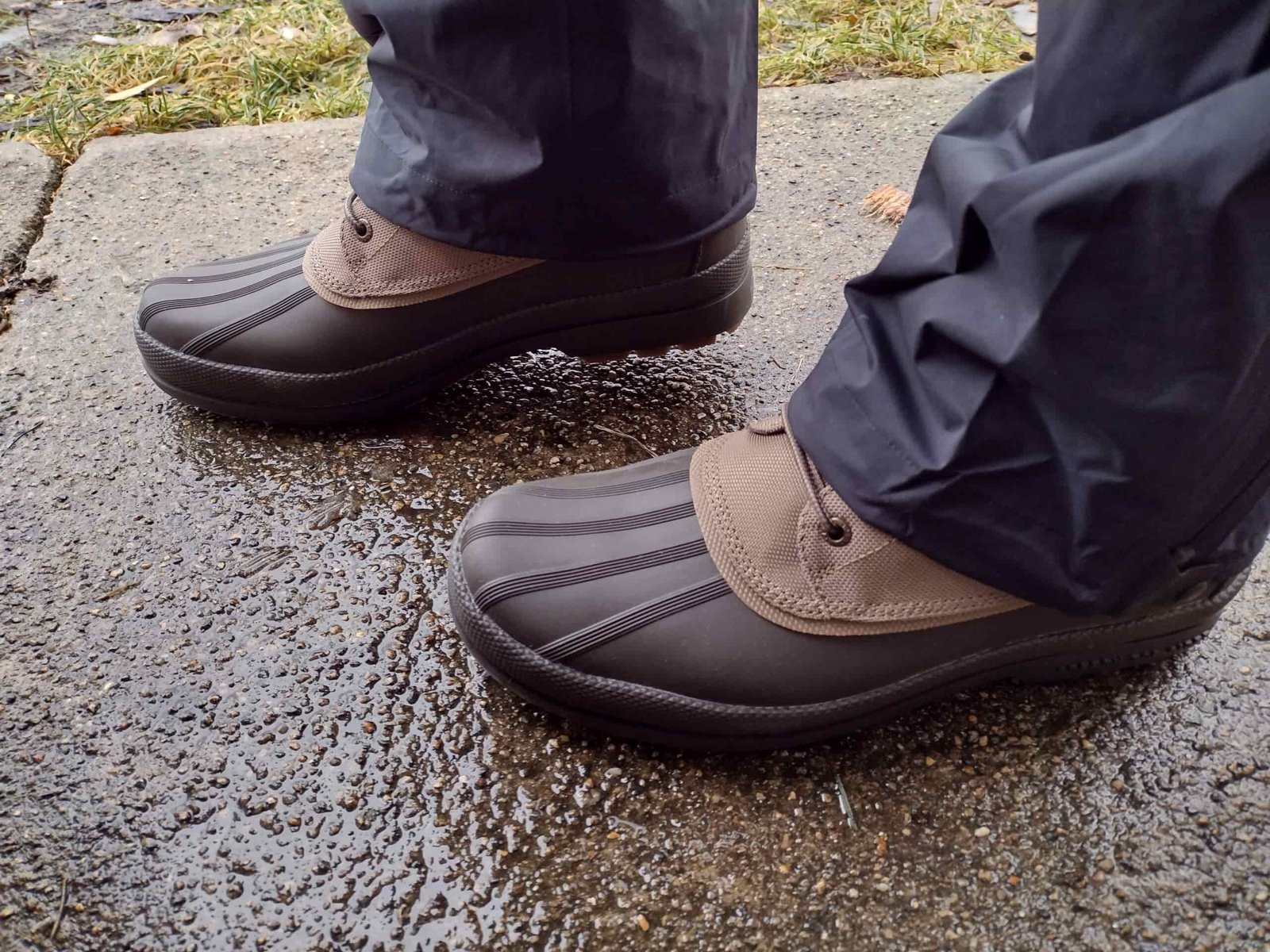 Ground level view of someone wearing the brown Sperry Cold Bay Chukka on a wet sidewalk.